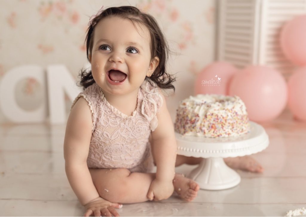 Lachendes Baby neben seiner Geburtstagstorte